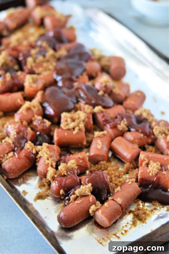 A baking sheet filled with chopped hot dogs, beautifully glazed with brown sugar and barbecue sauce, ready to be served.
