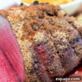 Homestyle Pot Roast Seasoning 7 Close-up of a sliced, seasoned roast beef with a crispy crust, enhanced with Pot Roast Seasoning, with a side dish blurred in the background.