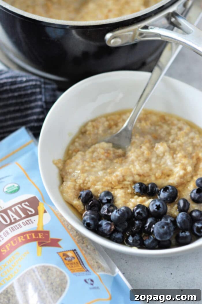 Perfect Steel Cut Oats 2 Bowl of steel cut oatmeal with blueberries, next to a package of steel-cut oats and a pot in the background, illustrating how to cook steel-cut oats.