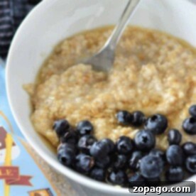 A bowl of oatmeal topped with blueberries sits enticingly next to a package of gluten-free oats, offering a perfect start to your day. Discover the delightful texture and taste that comes from knowing how to cook steel-cut oats just right.