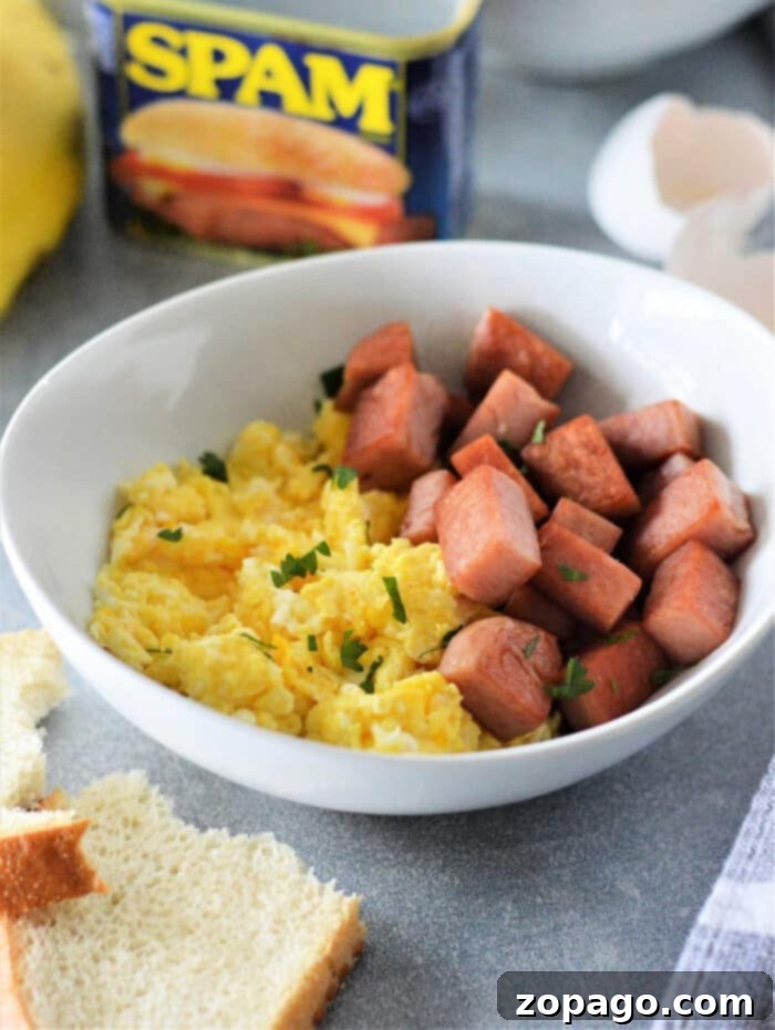 Quick and Tasty Spam and Eggs 2 A bowl of scrambled eggs and cubed Spam, with a Spam can in the background, brings the classic flavor to life—your ideal Spam and Eggs recipe.