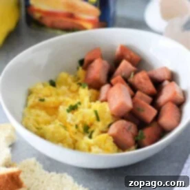 A bowl of scrambled eggs and cubed Spam, with a Spam can in the background, brings the classic flavor to life—your ideal Spam and Eggs recipe.