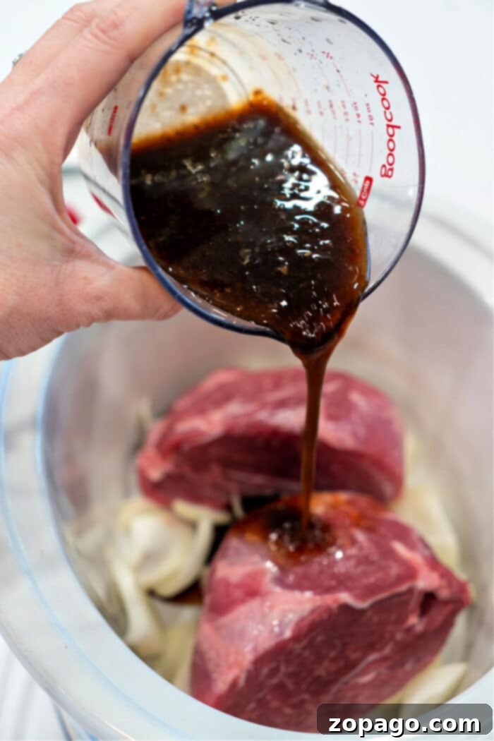 Pouring marinade over onions in a slow cooker, as if preparing a succulent pork picnic roast, infusing every layer with flavor.