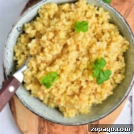 Fluffy Bulgur Every Time 7 A bowl of cooked bulgur, garnished with cilantro and artfully served on a wooden board with a fork beside it, showcases the simple elegance of this dish. Explore how to cook bulgur wheat and create delightful meals that blend texture and flavor seamlessly.