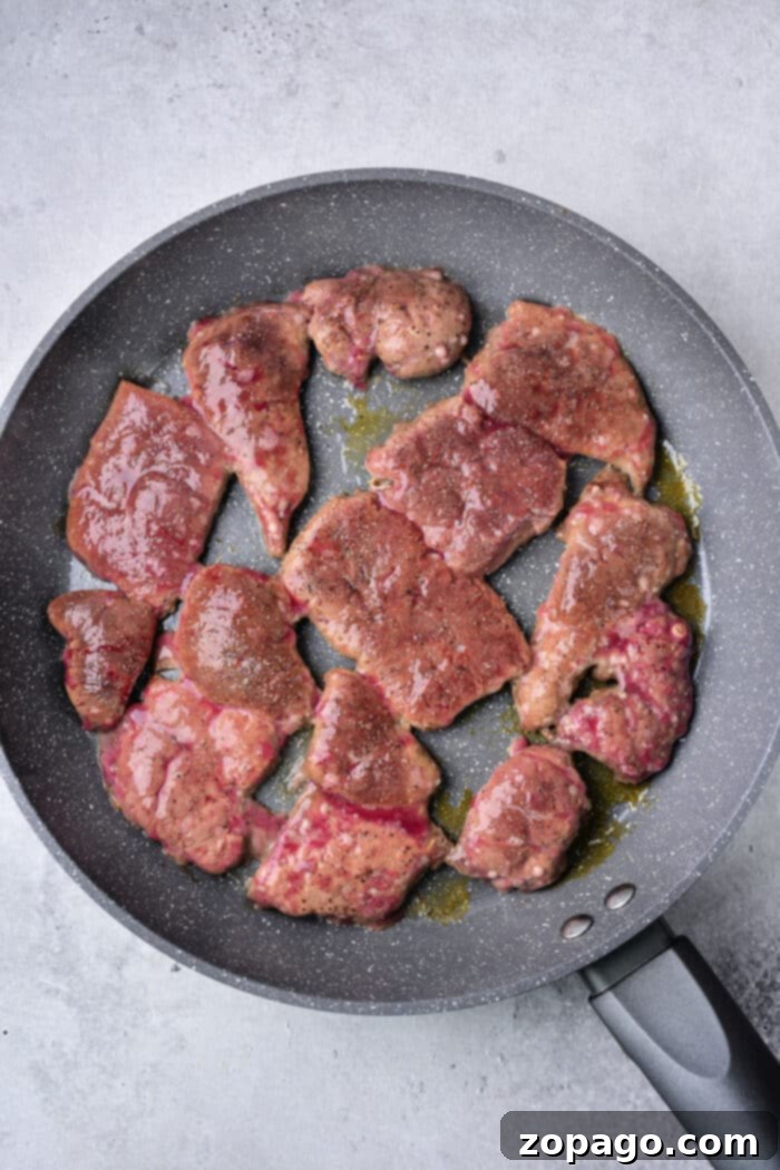 Venison Liver Delights 4 Close-up of pan-fried deer liver, golden-brown and perfectly seared, served alongside crispy onions and bacon.