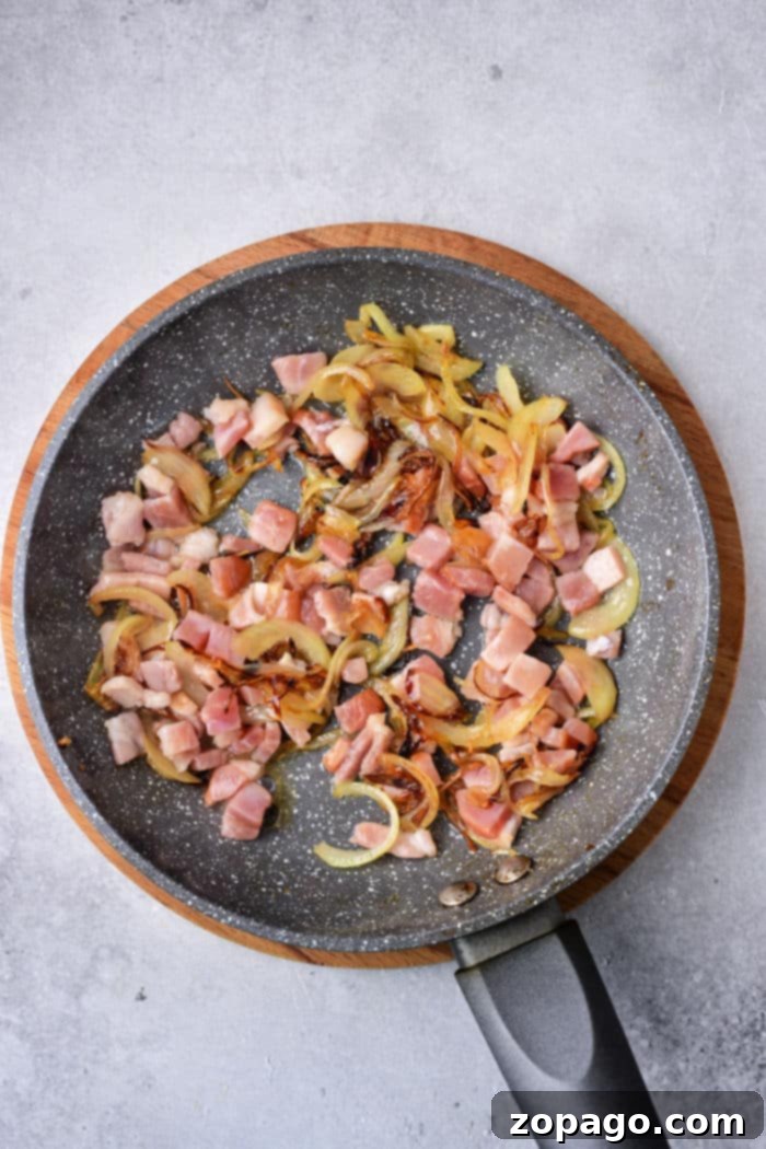 Venison Liver Delights 6 A frying pan with diced venison, sautéed onions, and tender slices of deer liver rests on a light gray background.