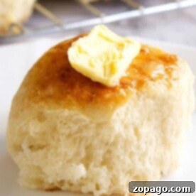 A buttered dinner roll on a plate, made even more delightful by starting with frozen rolls.