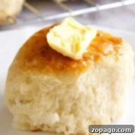 A buttered dinner roll on a plate, made even more delightful by starting with frozen rolls.