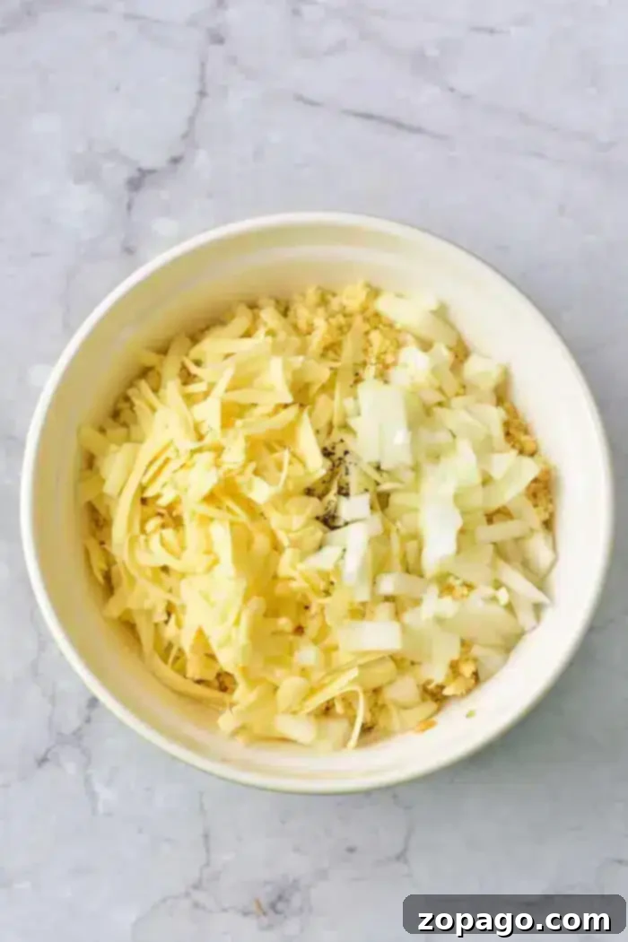 Easy 5 Ingredient Hash Brown Casserole 3 A white bowl holds a mixture of shredded cheese, finely chopped onions, and other ingredients, ready to be incorporated into a creamy and flavorful 5 Ingredient Hash Brown Casserole.