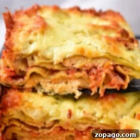 Two slices of cheesy, baked lasagna stacked on a black spatula, showcasing layers of pasta, sauce, and cheese, capture the essence of comfort food reminiscent of homemade baked ravioli delights.