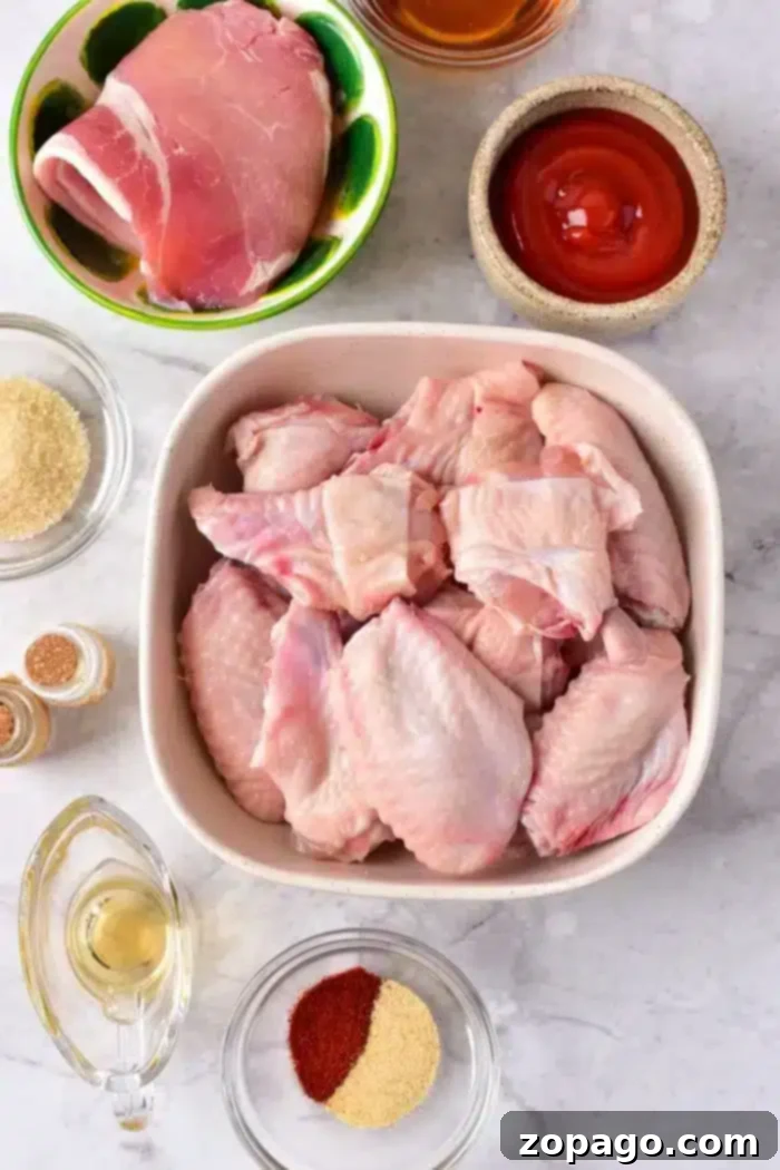 Perfect Oven Wings Cook Time Guide 2 A top-down view of raw chicken wings in a white dish, a bowl of raw boneless chicken thigh, a bowl of red sauce, a small bowl of brown sugar, a small bowl of spices, and a clear jug of oil.