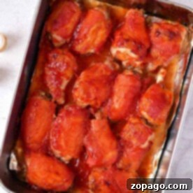 How Long to Bake Crispy Chicken Wings 7 Baked chicken wings topped with barbecue sauce rest in a rectangular metal tray on a marble surface, perfectly cooked like you’d time wings in the oven.