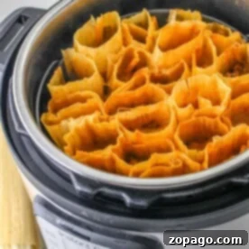 Tamales arranged in an Instant Pot, ready for steaming. Corn husks are neatly packed inside the stainless steel pot, as you ponder how long tamales take to cook to perfection.