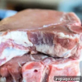 Close-up of two raw bone-in pork chops, perfectly seasoned and ready for cooking