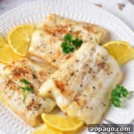 Three pieces of baked fish, cooked just right, with lemon slices and a sprinkle of parsley on a white plate. Perfectly timed like knowing how long to cook cod for that tender, flaky texture everyone loves.