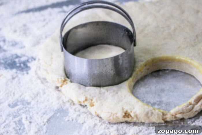 Hardees Copycat Biscuit Recipe 5 Biscuit dough from the Hardee's Biscuits recipe is shaped with a round cutter on a floured surface, ready for baking.