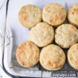 Biscuits, crafted with the classic Hardees Biscuits Recipe, are neatly arranged in a baking dish, resting on a white towel adorned with brown grid lines.