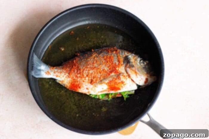Perfectly Crispy Whole Fish 3 Pan-frying a whole fish in a robust cast iron skillet, showcasing the golden-brown crust developing on the fish skin.