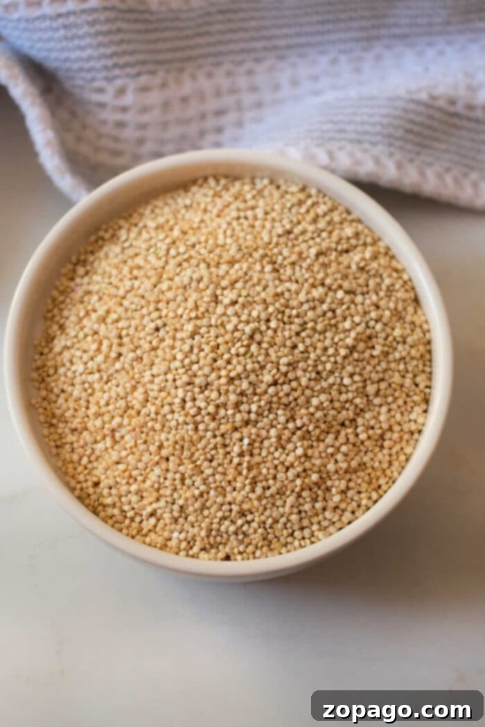 How Long to Cook Quinoa for Perfect Results 5 A bowl filled with uncooked quinoa rests on a countertop, accompanied by a textured cloth, all poised to reveal just how long to cook quinoa for that perfect fluffy texture.