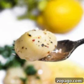 Close-up of a fork holding a perfectly seasoned smoked scallop, with a blurred lemon and greens in the background.