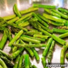 Pan-fried asparagus is sizzling to perfection in a stainless steel pan.