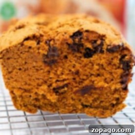 Close-up of a chocolate chip pumpkin bread loaf, crafted with spice cake mix, resting on a cooling rack.