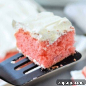 Slice of pink cake made from cake mix with strawberries, adorned with white frosting, sitting elegantly on a spatula, with a fresh strawberry nearby.