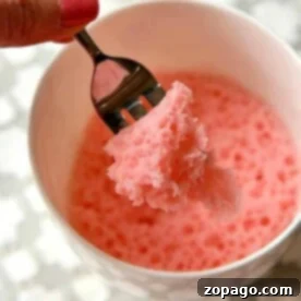 A hand holding a fork with pink mug cake over a white bowl showcases how to make a delightful treat using cake mix.