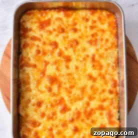 A baked cheesy casserole of savory delight, this Buffalo Chicken Dip rests invitingly in a rectangular metal dish atop a rustic wooden board.