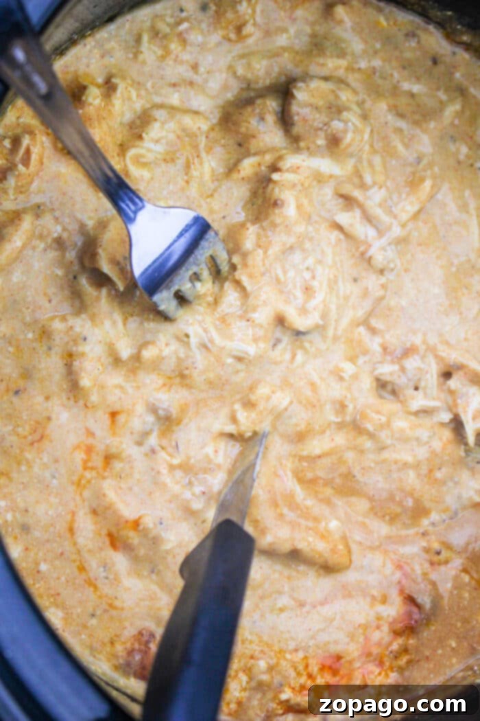 Creamy Crock Pot Chicken Noodle Bake 4 A slow cooker filled with creamy Slow Cooker Chicken Noodle Casserole, topped with melted cheese.