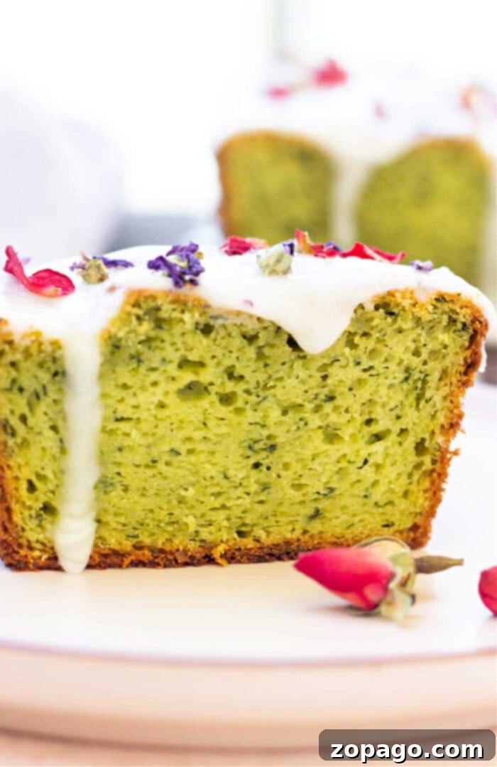 Velvet Avocado Cake 2 Slice of delightful avocado cake with white frosting, topped with dried flowers, presented elegantly on a plate.
