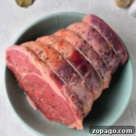 Mastering Roast Cooking Times 8 A bowl showcasing a seasoned raw beef roast with visible spices, ready for its transformation into a succulent dish. Accompanied by aromatic bay leaves and a pepper shaker, it sets the stage for those eager to discover how to cook a roast perfectly.