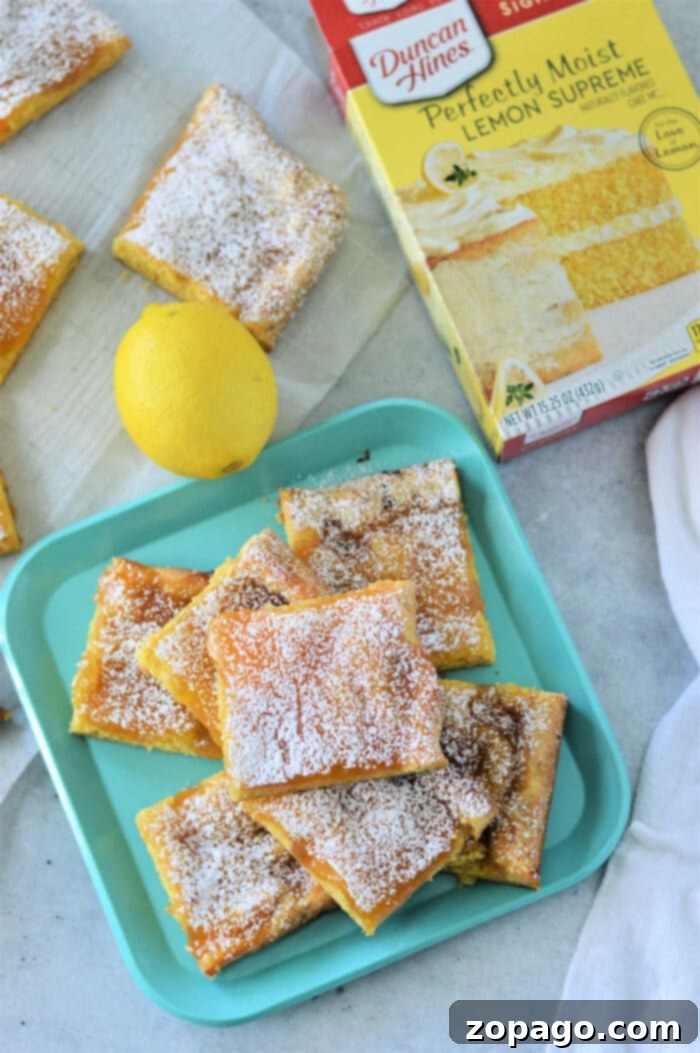 Effortless Cake Mix Lemon Bars 6 Lemon bars with cake mix dusted with powdered sugar rest elegantly on a blue tray, accompanied by a fresh lemon and the cake mix box for inspiration.