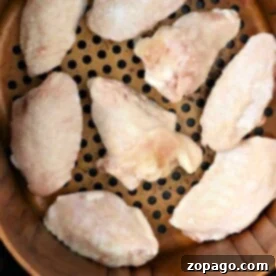 Crispy Air Fryer Frozen Chicken 6 Frozen chicken in an air fryer basket, wings arranged perfectly before cooking.