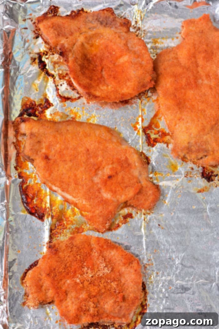 Thin Pork Chops in the Oven: Optimal Cooking Times 6 A perfectly cooked thin pork chop with a golden breading, sliced to reveal its moist interior, on a plate with garnishes.