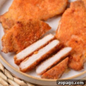 Slices of breaded thin pork chops are artfully arranged on a plate, with whole pieces in the background, reminiscent of how long to cook thin pork chops in the oven for that perfect golden finish.