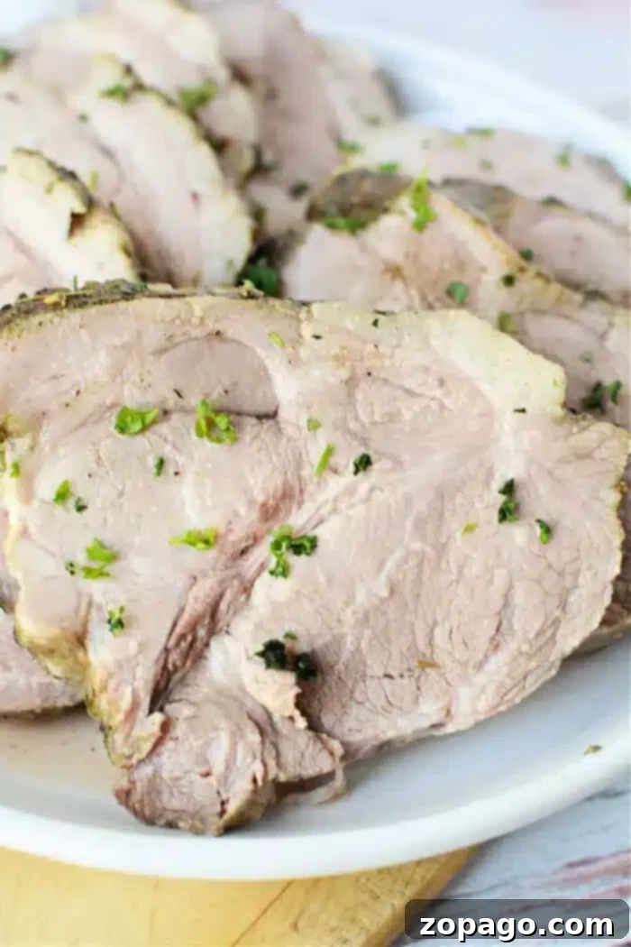 Set It and Forget It 3-Ingredient Pork Roast 2 Slices of roasted pork, straight from the slow cooker, are garnished with chopped herbs and arranged on a white plate. The meat appears tender and well-cooked, inviting a hearty meal.