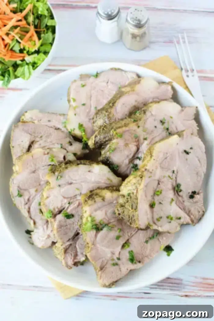 Set It and Forget It 3-Ingredient Pork Roast 6 A white plate presents several perfectly cooked slices of 3 Ingredient Pork Roast Slow Cooker-style pork, beautifully garnished with fresh chopped herbs.