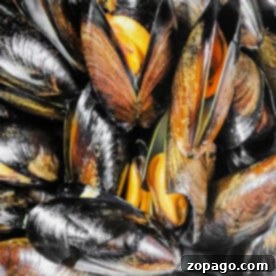 Close-up of opened mussels with glossy black shells and bright orange flesh, perfect for those learning how to cook frozen mussels.