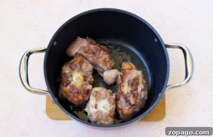 Braised Oxtail in a Dutch Oven 3 Dutch Oven Oxtail Recipe - Close-up of cooked oxtails with broth and herbs.