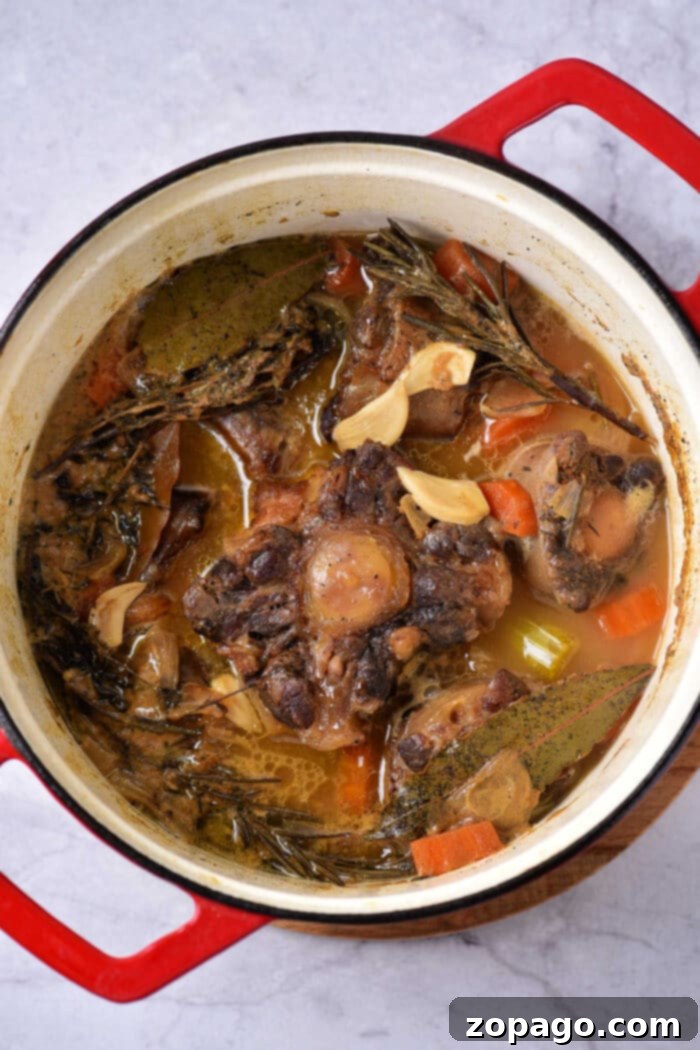 Slow-Cooked Oxtail Perfection 5 how to braise oxtails: A step-by-step image of oxtail pieces being seared in a Dutch oven before braising.