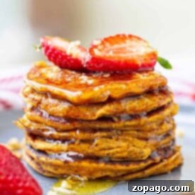 Sweet Potato Pancakes: A Unique Recipe 7 A stack of sweet potato pancakes topped with sliced strawberries and drizzled with syrup sits enticingly on a plate.