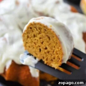 A slice of pumpkin Bundt cake with cream cheese frosting rests enticingly on a spatula, made effortlessly delightful with a convenient cake mix.