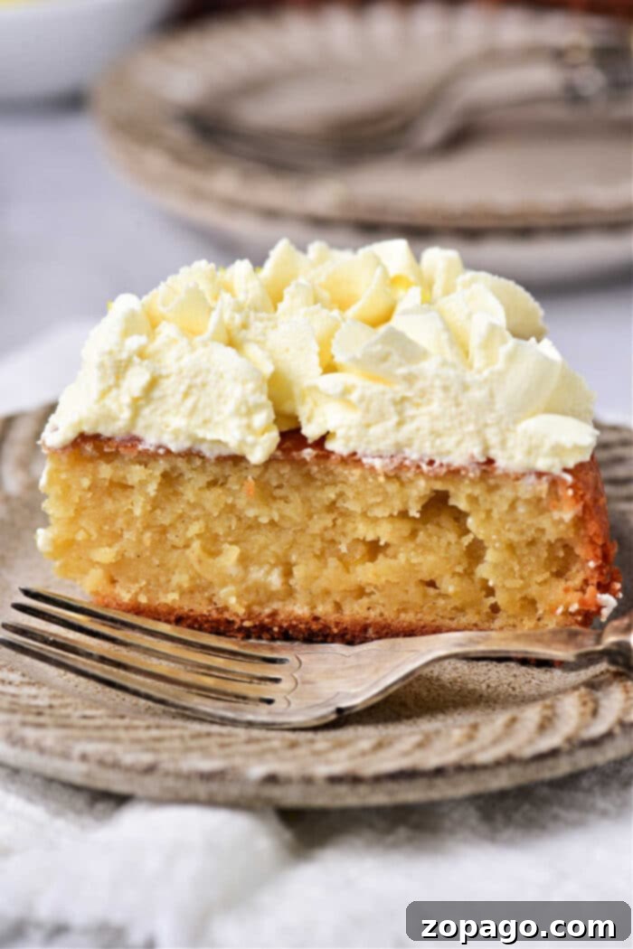 Luscious Lemon Curd Cake 6 A slice of lemon cake with whipped cream and lemon curd on a rustic plate, accompanied by a fork.