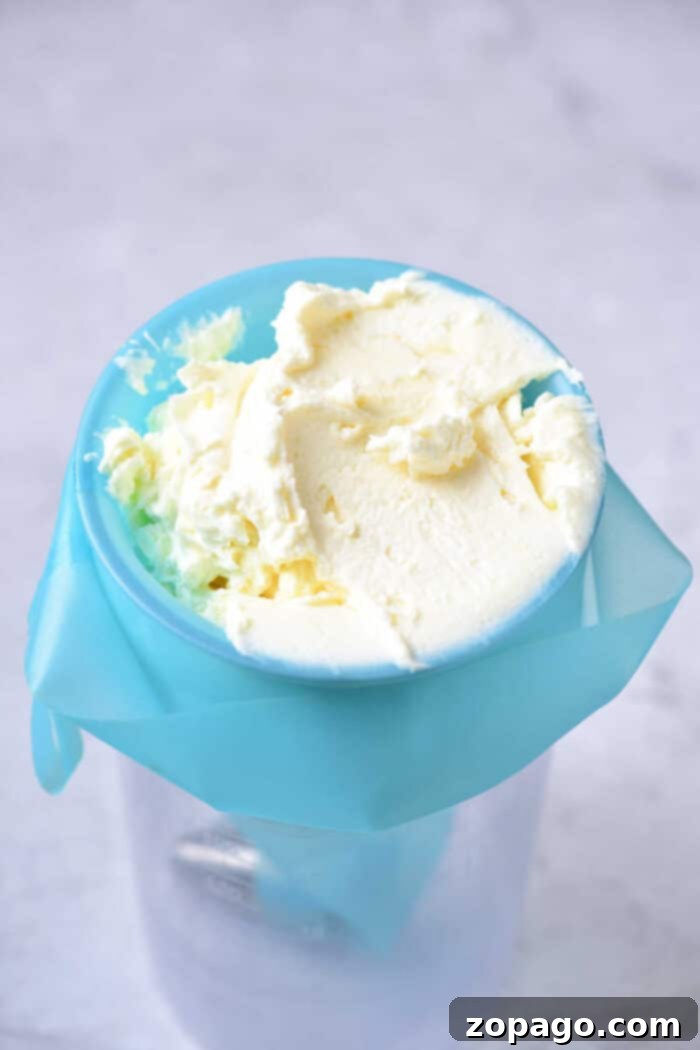 Luscious Lemon Curd Cake 7 Homemade frosting in a blue churn with cream residue on top, resembling the rich texture of a Lemon Curd Cake, set against a light background.
