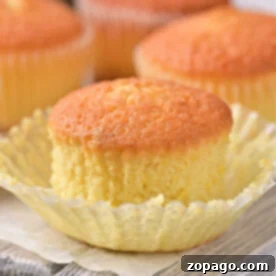 Zesty Lemon Muffins 6 Golden lemon muffin recipe, one with an open wrapper, rest elegantly on a wooden board.