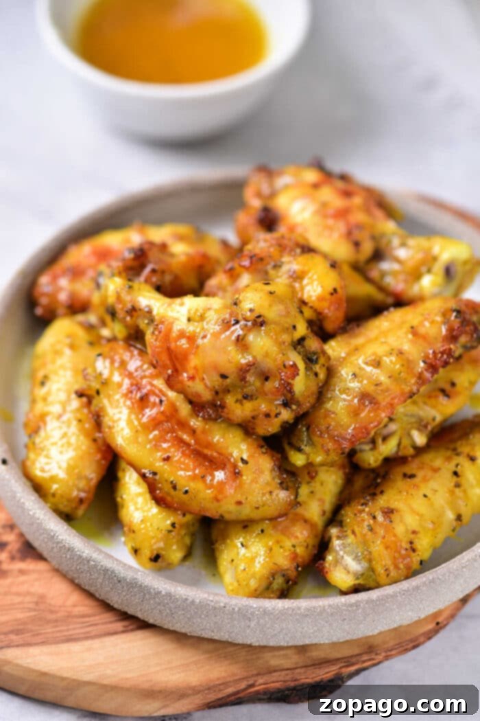 Honey Glazed Lemon Pepper Wings 2 Honey Lemon Pepper Wings, golden brown and crispy from the air fryer, garnished with fresh herbs and lemon wedges, ready to serve.