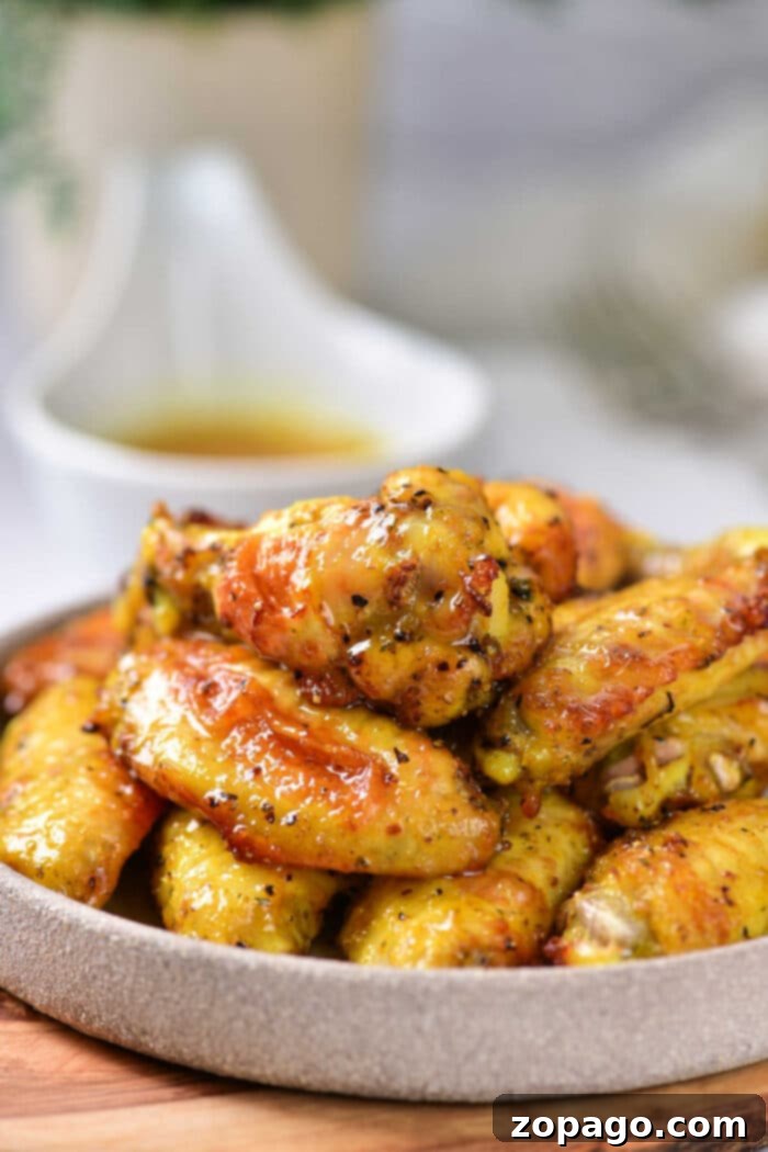 Honey Glazed Lemon Pepper Wings 6 A close-up shot of hot honey lemon pepper wings, glistening with sauce and topped with fresh green herbs, promising a fiery and flavorful bite.