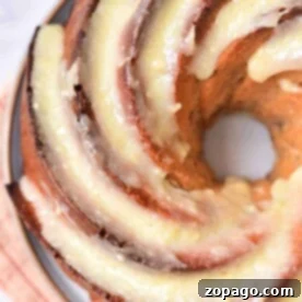 Close-up of a freshly baked bundt cake, glazed to perfection, on a plate with a striped cloth underneath—its the perfect Fresh Apple Cake Recipe in a Bundt Pan.