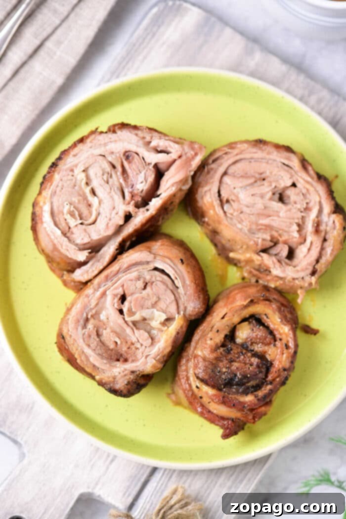Slow-Braised Lamb Breast 7 Four slices of cooked, rolled lamb rest enticingly on a green plate, reminiscent of a well-crafted lamb breast recipe.